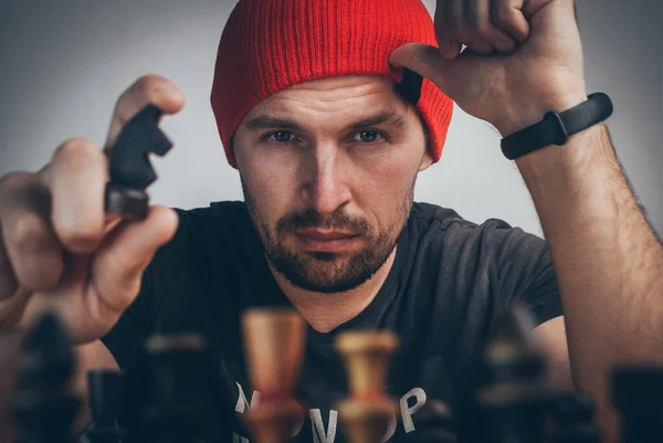 Un joueur d'échecs dans une casquette rouge déplace un chevalier noir conduisant le roi blanc dans un coin — Photo