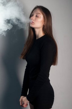 Güzel genç manken beyaz arka planda duman çıkarıyor.