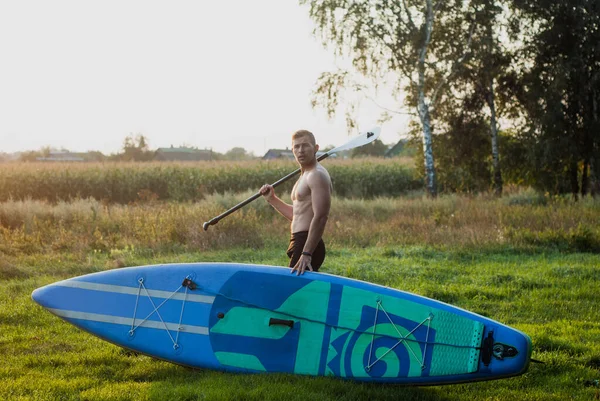 Plonsbord. een surfer staat met een plank en een peddel op de rpssvet — Stockfoto