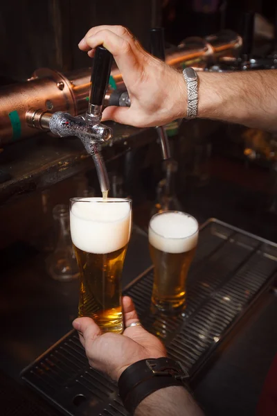 De barman giet een biertje in glas — Stockfoto
