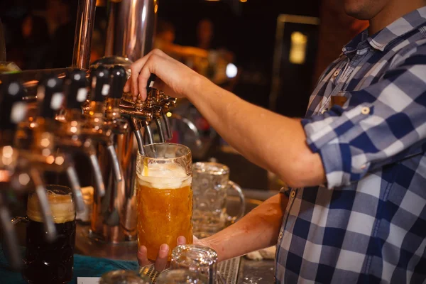 O barman serve uma cerveja da torneira — Fotografia de Stock