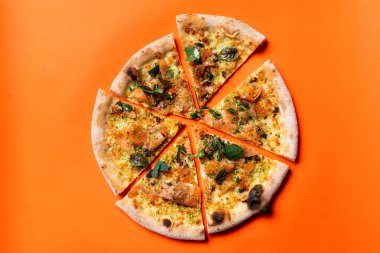 Dilimlenmiş pizza, parlak bir kağıdın üzerinde duran bölümler, stüdyo çekiminin hemen üstünde.