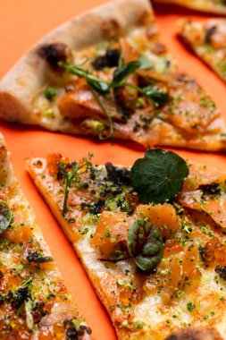 Güzel iştah açıcı füme somon pizzası. Arka arkaya yerleştirilmiş, turuncu arka planda yakın plan.
