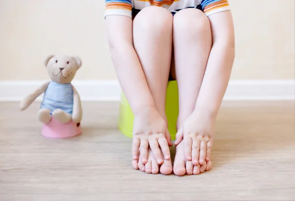 Gros plan des jambes de l'enfant assis sur le pot — Photo