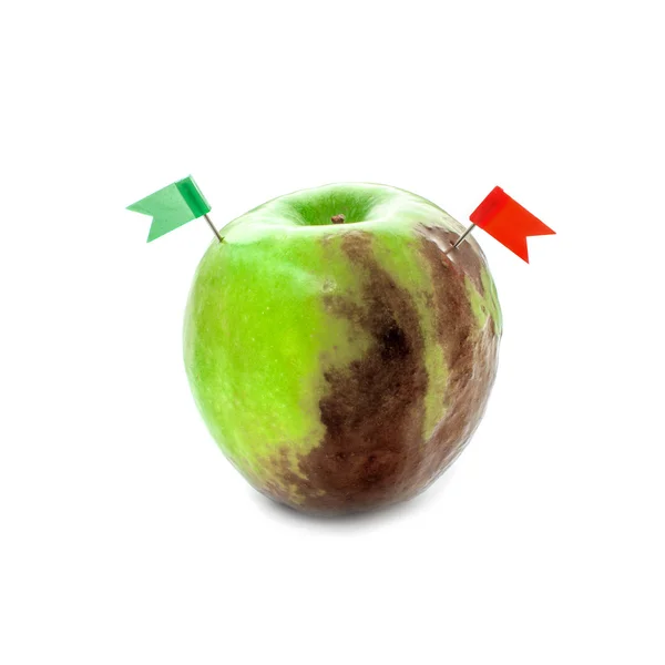 Полугнилое зеленое яблоко с двумя флагами — стоковое фото