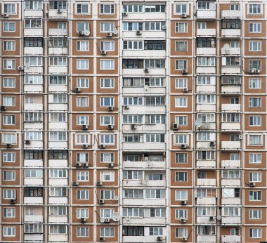 Birçok penceresi olan çok katlı bir binanın ön cephesi. Önceden yapılmış betondan yapılmış eski evler. Ucuz daireler.