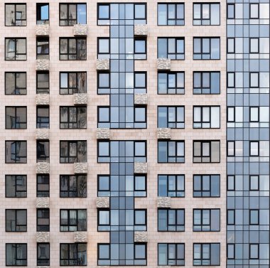 Şehir binasının ön cephesi ışık taşıyla karşılandı. Yüksek temiz pencereler mavi gökyüzünü ve bitişik ofisi yansıtır.