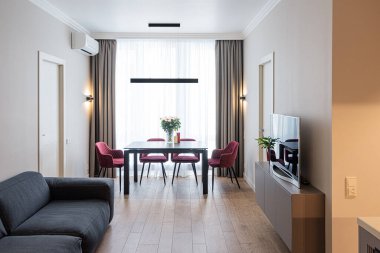 Büyük parlak pencereli modern oturma odası. Televizyon ve rahat kanepe..