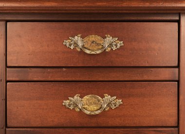Wood furniture. Detail of closed drawers with ornate brass handles