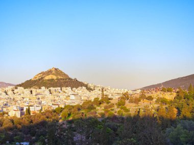 Atina 'nın panoramik manzarası Lycabettus Dağı tepesi ve Areopagus tepesi altın günbatımı ışığı altında insanlarla dolu.