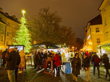 Prag, Çek Cumhuriyeti - 13 Aralık 2024: İnsanlar süslü ağaç ve bayram tezgahlarıyla gece festival Noel pazarının keyfini çıkarıyorlar
