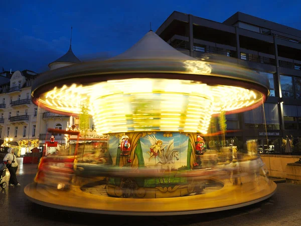 Renkli atlıkarınca. Dönmekten dolayı hareket bulanıklığı var. Şehir meydanında akşam gökyüzüne karşı parlıyor.