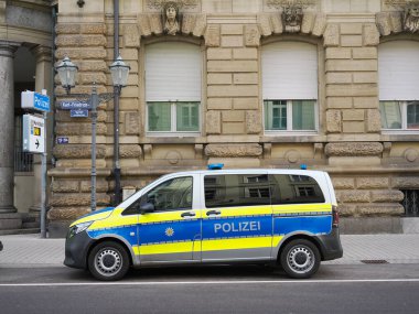 Mavi ve sarı Alman polis minibüsü tarihi taş binanın önüne park edilmiş.