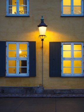 Günbatımında aydınlık pencereleri ve klasik sokak lambasıyla geleneksel Avrupa binası cephesi