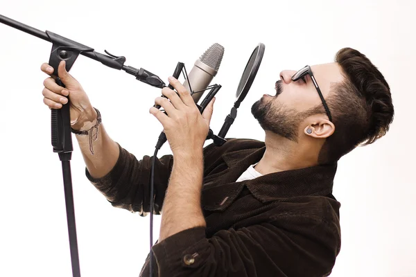Ung man klädd i en brun kappa och glasögon sjunger en sång — Stockfoto
