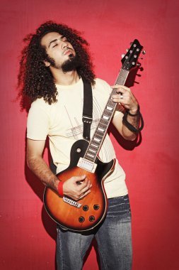 Güzel uzun kıvırcık saçlı guit oynarken tutkulu gitarist