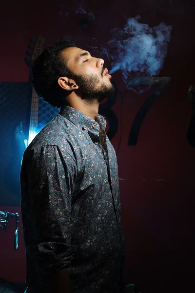 Hombre joven fumando cigarrillo sobre fondo oscuro — Foto de Stock