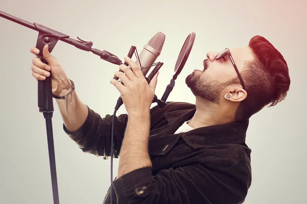 Joven vestido con un abrigo marrón y gafas cantando una canción — Foto de Stock