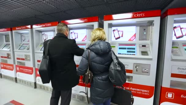 Dos personas están comprando boletos de la máquina de billetes que viaja en tren del aeropuerto — Vídeo de stock