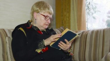 Kanepede gözlük kullanan yaşlı kadın kıdemli eski bir okuma yaş yaptırın