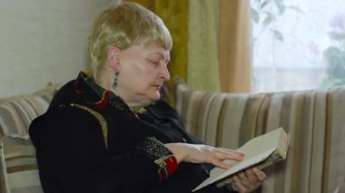 Kanepeye, yakın çekim gözlük kullanan yaşlı kadın kıdemli eski bir okuma yaş yaptırın