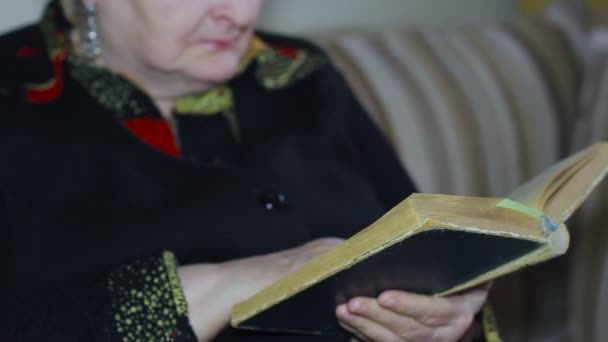 Anciana de la tercera edad leyendo un libro viejo con anteojos, primer plano — Vídeos de Stock