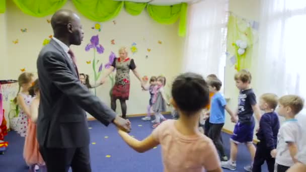 Małe dzieci kaukaski taniec w kręgu z Afryki nauczyciela w przedszkolu — Wideo stockowe