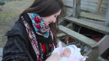 Zavallı ahşap ev ve Holding yeni doğan bebek kız basamaklarda genç güzel esmer kız annesi oturma. Rusya. Portre