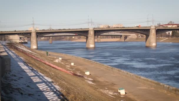 Egy rakpart a folyó mellett. Nagy híd, amin sok autó megy. Késő tél — Stock videók