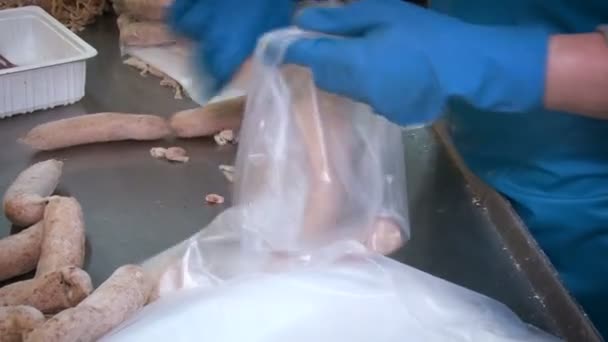 Un abattoir. Un homme collecte des saucisses dans des paquets. — Video