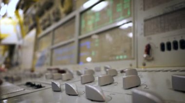 Denizaltı kontrol paneli. Bir adam göstergelerle ekranlara bakar ve sorunları düzeltir