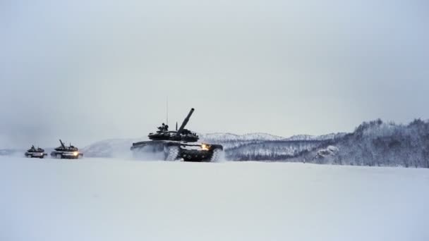 Met sneeuw bedekte schietbaan. Tanks rijden in de winter over het veld — Stockvideo