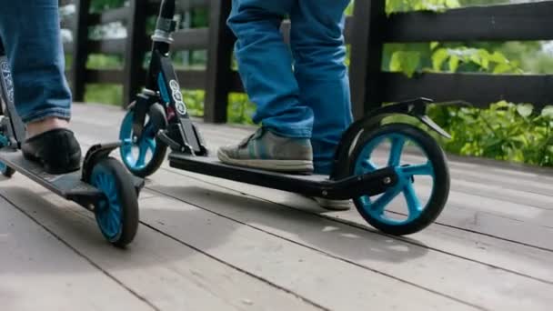 Die Holzbrücke ist braun. Kind und Frau fahren Roller. Nahaufnahme — Stockvideo