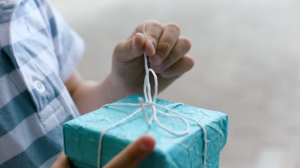 Presente com embalagem azul. Um homem abre um presente amarrado com cordas. A Rússia. Vista de perto — Vídeo de Stock