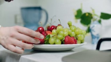 Meyve tabağı. Masada meyve tepsisi yapan kadın. Yakın görünüm