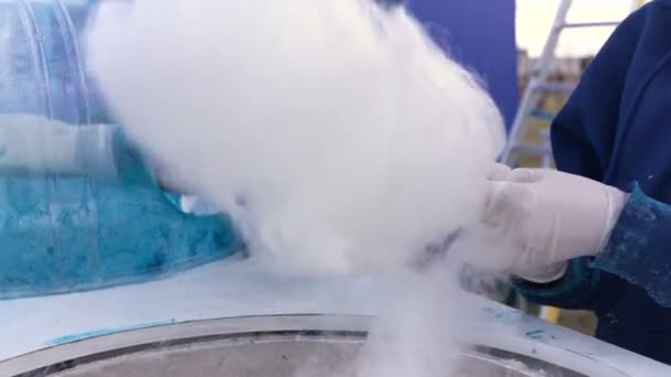 Two people working outside. Men make cotton candy on a special machine. Closeup view — Stock Video