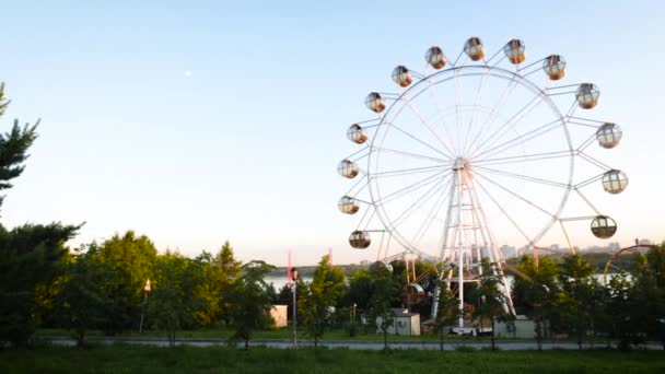 Панорама невеликого парку розваг на березі річки. Вид на колесо Ферріса, літній день. — стокове відео