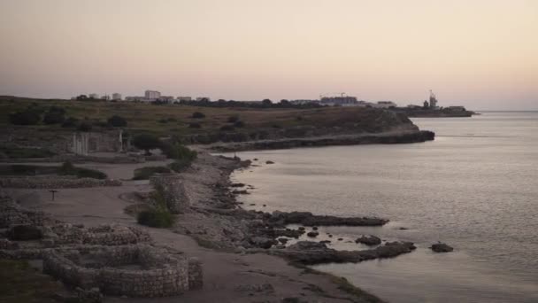 Panorama krymskiego brzegu morza z starozytnymi ruinami. Na tle miasta i morza. Chersonesos, wieczór, morze — Wideo stockowe