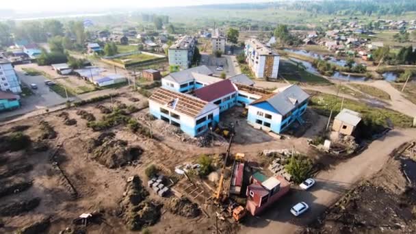 Widok z góry na plac budowy. Mała wioska po huraganie. Sprzęt budowlany, samochody, domy, las w tle — Wideo stockowe