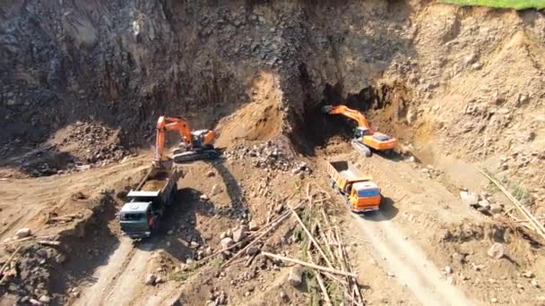 Aerial view of a quarry with working equipment. The bulldozer fills the truck with soil. Construction industry, summer day — Stock Video