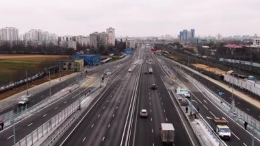 Patika şehre doğru gidiyor. Yolun yakınındaki evler. Birçok araba pistin havadan görüntüsü boyunca gidiyor.