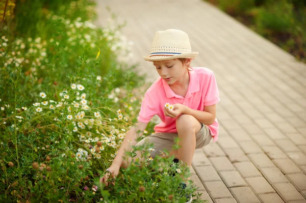 Menino sentado nas flores na primavera — Fotografia de Stock