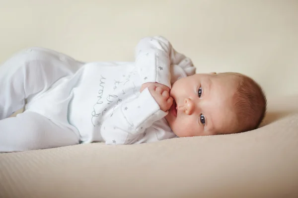 Дитина лежить на яскравій площині в білій піжамі — стокове фото