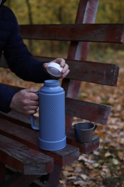 Sonbahar pikniğinde mavi-gri bir termos ve teneke bardak.