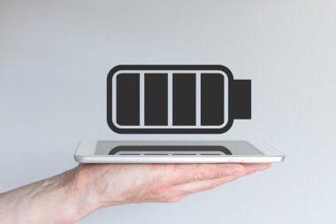 Concept of battery life for mobile devices. Hand holding modern smart phone or tablet.