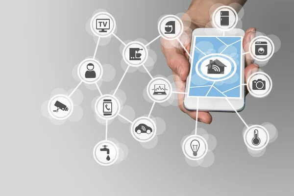 El ile akıllı ev konsepti internet üzerinden ev aletleri kontrol etmek için modern akıllı telefon tutarak