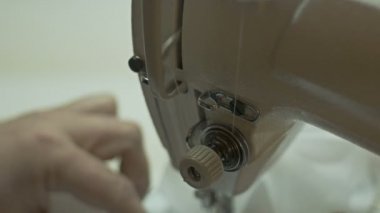 Adam dikiş makinesi üzerinde çalışıyor.