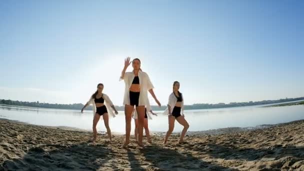 Tańca czterech dziewcząt na piaszczystej plaży w pobliżu jeziora o świcie — Wideo stockowe