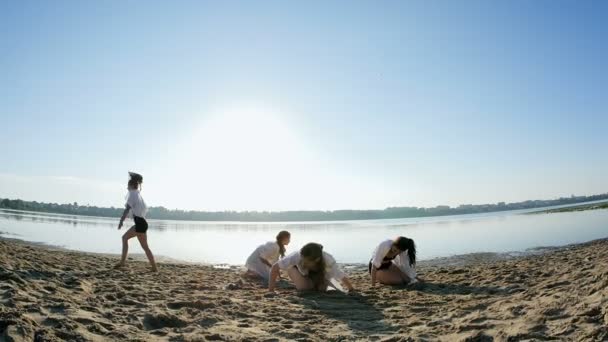 Danse performance de quatre filles sur la plage de sable près du lac à l'aube — Video