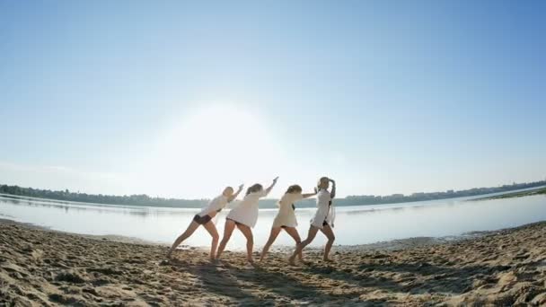 夜明けの湖の近くの砂浜に 4 人の女の子のダンス パフォーマンス — ストック動画